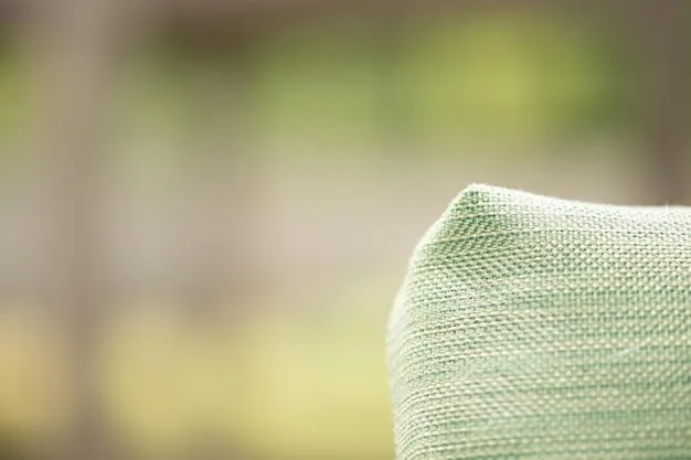 A close-up of a stylish SHEIN outdoor throw pillow on a patio chair, with a blurred background of string lights and green foliage, emphasizing texture and comfort.