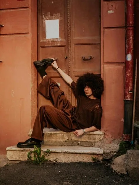 A stylish person wearing a chic, layered outfit composed of thrifted items, confidently posing in an urban setting, showcasing their individual style.