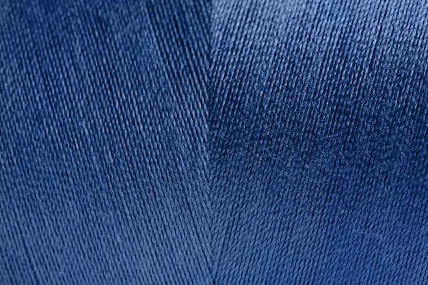 Detailed close-up of a dark blue denim fabric, clearly showing the diagonal twill weave pattern and the texture of the threads.