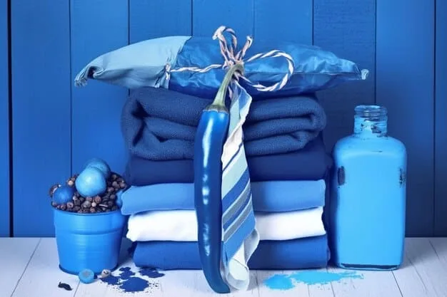 A neatly folded pile of various clean, laundered fabrics, possibly with some laundry detergent or fabric softener bottles in the background, symbolizing care and maintenance.