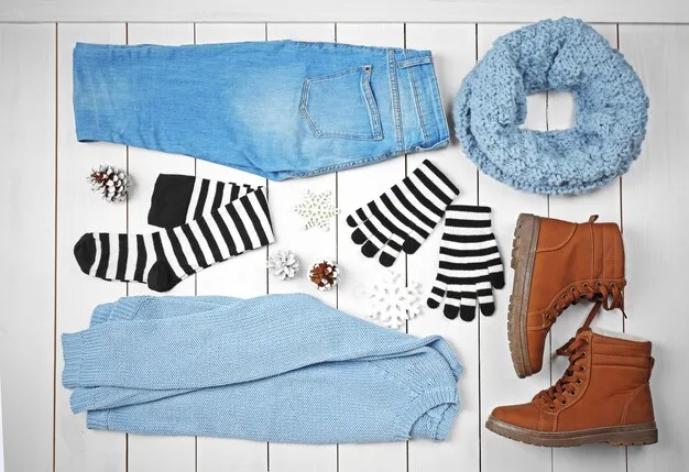A detailed flat lay of various clothing items, including a trench coat, a striped shirt, jeans, and a cashmere sweater, all neatly arranged to showcase their mix-and-match potential for different seasons.