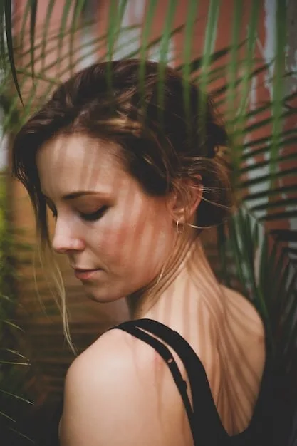 A woman with warm skin undertones wearing a vibrant olive green dress, radiating confidence and warmth. The background is softly blurred with golden light, highlighting her natural glow.
