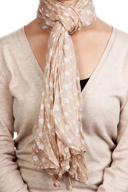 A close-up shot of a intricately patterned silk scarf tied around a woman's neck, adding a splash of color to her neutral-toned blouse.