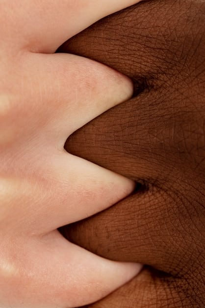 A close-up shot of a hands intertwined, showcasing different skin tones and textures. The background is blurred, emphasizing the connection and unity despite the differences. This image represents the strength and beauty found in diversity within a community.