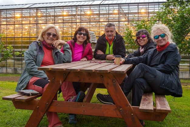 A colorful mosaic bench in a public park is surrounded by people of different ages and ethnicities. Some are sitting and chatting, while others are admiring the artwork. The scene depicts a sense of community and inclusivity.