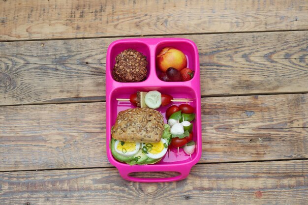 A close-up shot of a school lunch tray featuring a colorful array of healthy options, including whole-grain bread, a lean protein source (like grilled chicken or fish), a variety of fresh vegetables (such as broccoli, carrots, and bell peppers), and a piece of fruit.