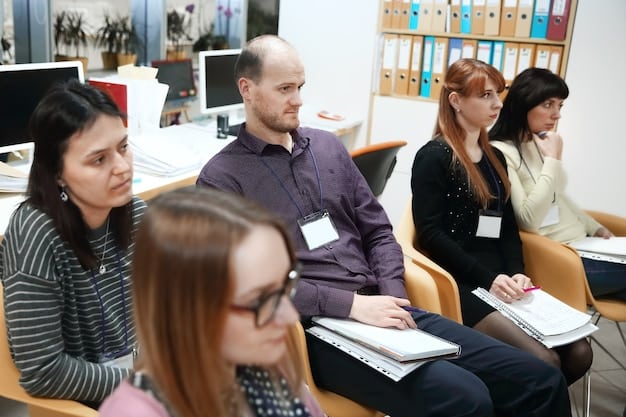 A group of teachers participating in a professional development workshop. They are working in small groups, discussing strategies for implementing new teaching techniques and using laptops and tablets to access resources. The atmosphere is collaborative and engaging.