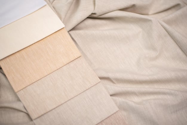 Various fabric swatches laid out on a bed, illustrating different bedding materials like cotton, microfiber, and linen with labels