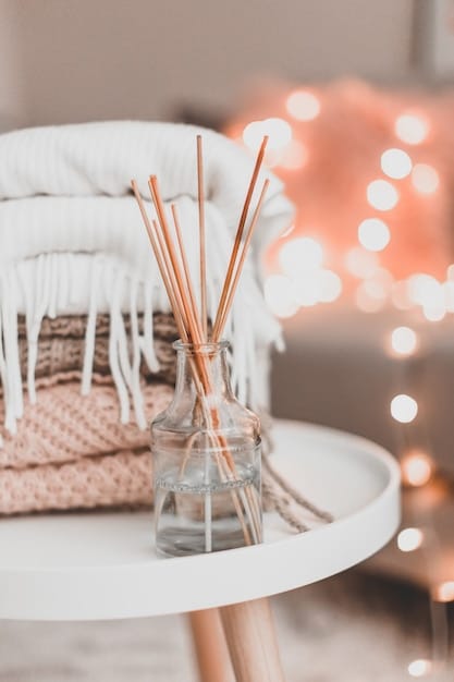 A close-up of a stylish reed diffuser with natural reeds emanating a gentle scent, set against a blurred background of a modern bedroom interior with soft bedding and minimalistic decor.