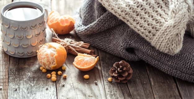 A beautifully arranged collection of autumn-themed home fragrance items including a pumpkin-spiced candle, cinnamon sticks, and dried orange slices, on a rustic wooden table.