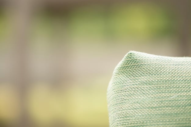A close-up of a stylish SHEIN outdoor throw pillow on a patio chair, with a blurred background of string lights and green foliage, emphasizing texture and comfort.