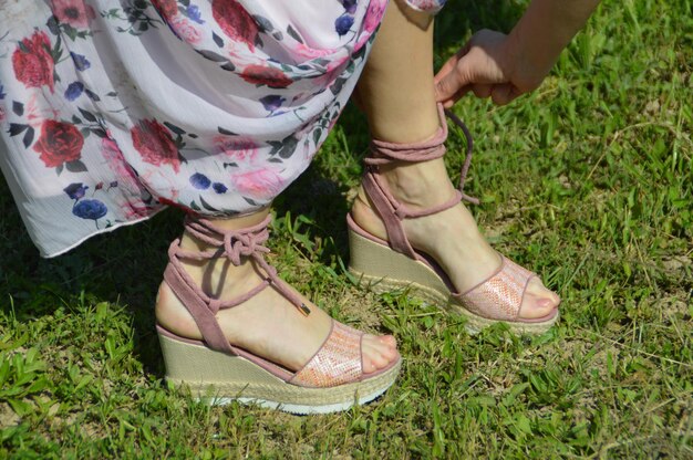 A pair of trendy platform sandals in a neutral color, styled with a flowing summer dress, on a sunny outdoor setting.