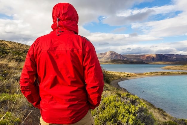 A person wearing a high-performance, weather-resistant hiking jacket with breathable pants, standing on a scenic mountain trail, demonstrating appropriate clothing for adventurous travel.