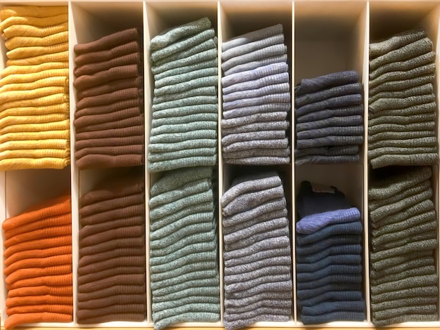 A detailed shot of closet shelves with perfectly folded sweaters and T-shirts, neatly stacked using vertical folding techniques, showcasing organized and easily accessible garments.