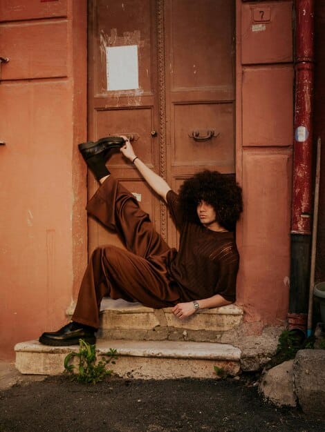 A stylish person wearing a chic, layered outfit composed of thrifted items, confidently posing in an urban setting, showcasing their individual style.