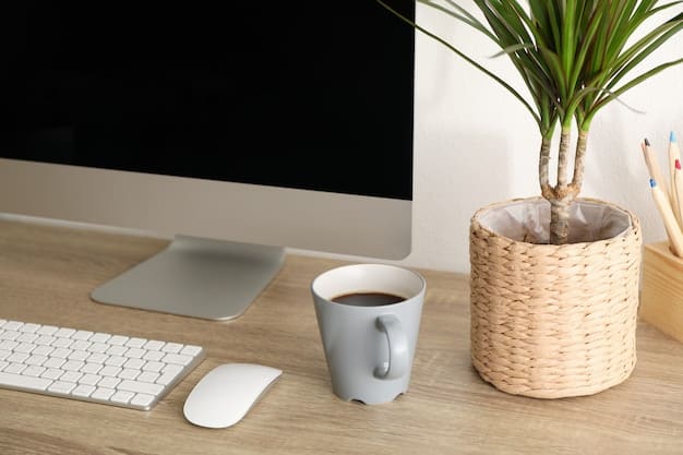 A minimalist standing desk converter on a wooden desk, raised to standing height with a laptop and external monitor on it. A cup of coffee and a small plant are also visible.